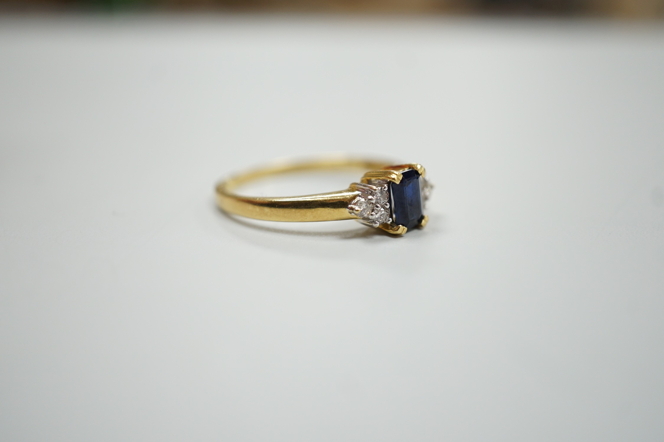 A modern 18ct gold and single stone sapphire set ring, with six stone diamond set shoulders, size R, gross weight 3.2 grams.